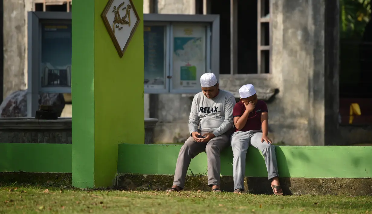 Orang-orang berdoa saat ziarah di Kuburan Massal Ulee Lheue selama peringatan 14 tahun tsunami Aceh di Banda Aceh, Rabu (26/12). Sejumlah warga mengenang keluarga yang meninggal akibat bencana tsunami di Aceh 14 tahun silam. (Chaideer MAHYUDDIN / AFP)