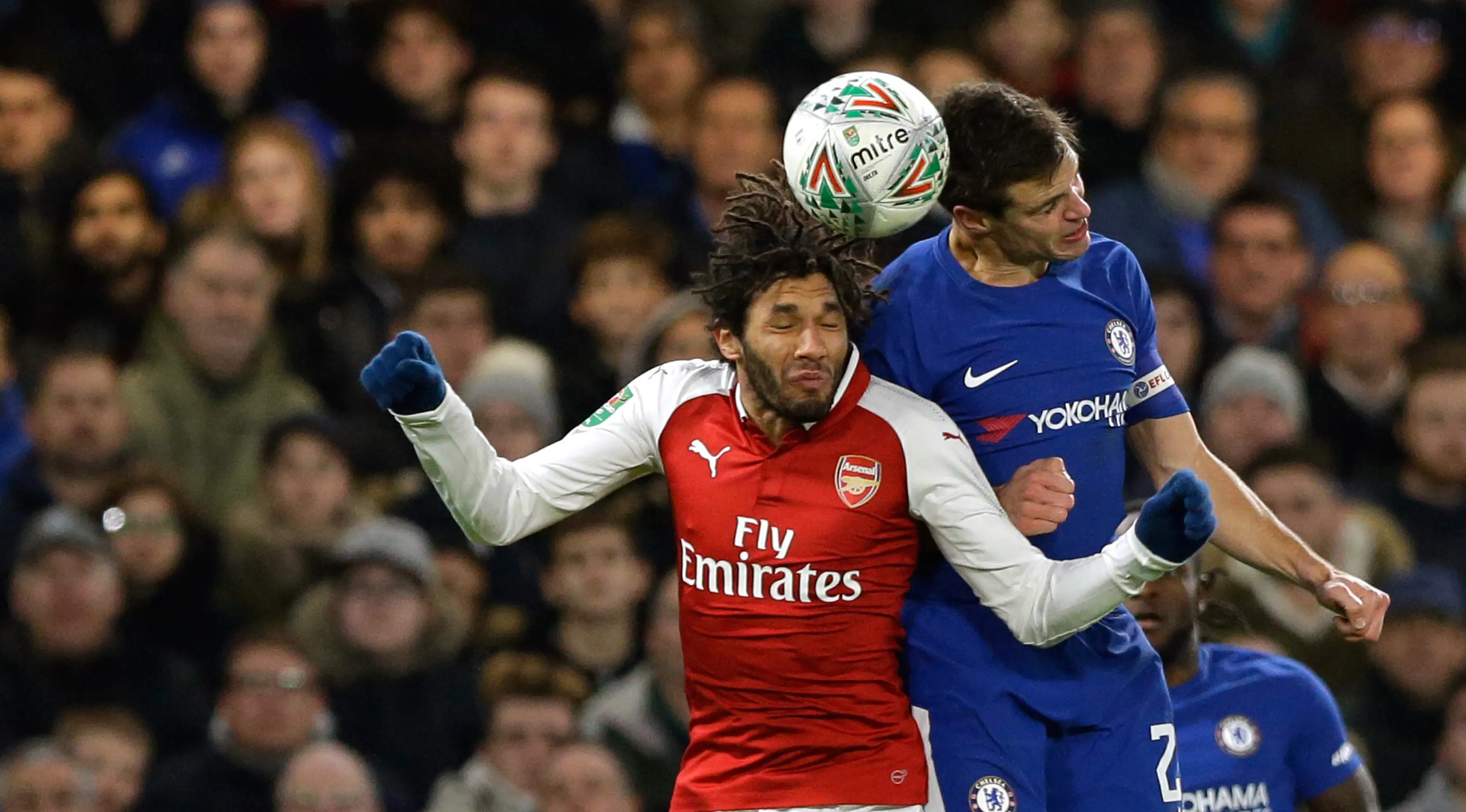 Pemain Arsenal, Mohamed Elneny melompat untuk merebut bola dari pemain Chelsea, Cesar Azpilicueta pada laga semifinal pertama Piala Liga Inggris di Stadion Stamford Bridge, Rabu (10/1). Chelsea harus puas diimbangi Arsenal 0-0. (AP/Kirsty Wigglesworth)