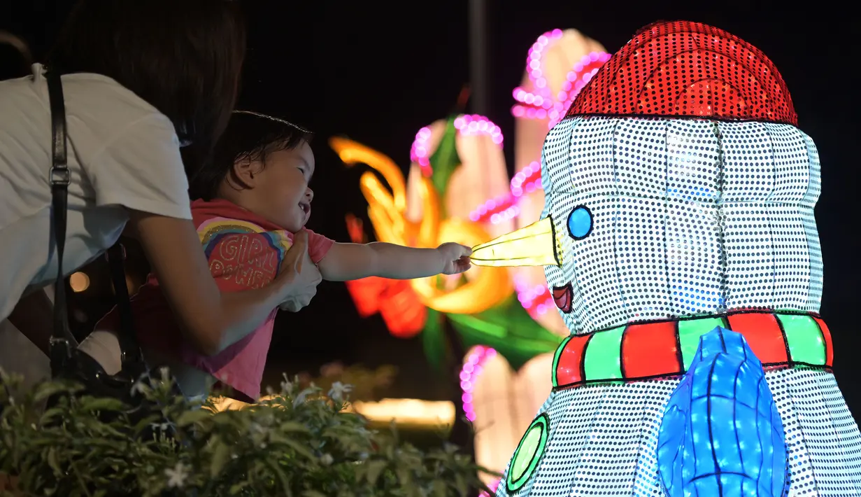 Seorang anak perempuan menyentuh dekorasi cahaya manusia salju di "Festival Cahaya" yang diadakan di Jurong Lake Gardens, Singapura, pada 20 Desember 2020. "Festival Cahaya" berlangsung dari 18 Desember 2020 hingga 3 Januari 2021. (Xinhua/Then Chih Wey)