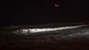 Seorang wisatawan meluncur ke dalam gulungan ombak saat berselancar di pantai La Pampilla, ibu kota Peru, Lima, 2 Maret 2017. Sekelompok peselancar hardcore memilih bermain selancar pada malam hari. (AP Photo/Rodrigo Abd)