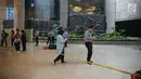 Sejumlah orang berjalan dekat garis polisi yang dipasang setelah ambruknya Selasar Tower II Gedung Bursa Efek Indonesia (BEI), Jakarta, Senin (15/1). Polisi pun mengerahkan tiga anjing pelacak ke lokasi ambruknya balkon BEI. (Liputan6.com/Johan Tallo)