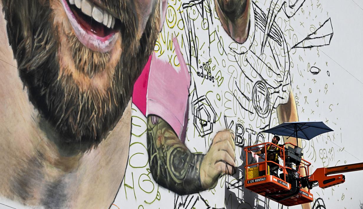 <p>Seniman Argentina, Maximiliano Bagnasco sedang mengerjakan mural besar bergambar Lionel Messi di Wynwood, Miami, 10 Juli 2023. La Pulga akan melakukan debutnya di Inter Miami pada 21 Juli di Piala Liga. (AFP/Chandan Khanna)</p>