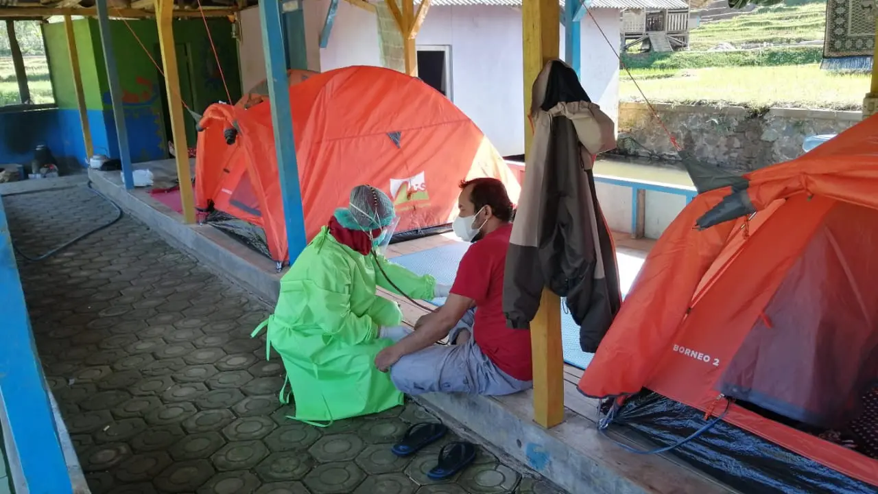 Nampak petugas medis tengah memberikan perawatan berkala bagi salah satu pasien Covid-19 di area isoman dari Tenda di area wisata air tubin, Desa Bentar Peundeuy, Desa Bojong wilayah Kecamatan Banjarwangi, Garut.