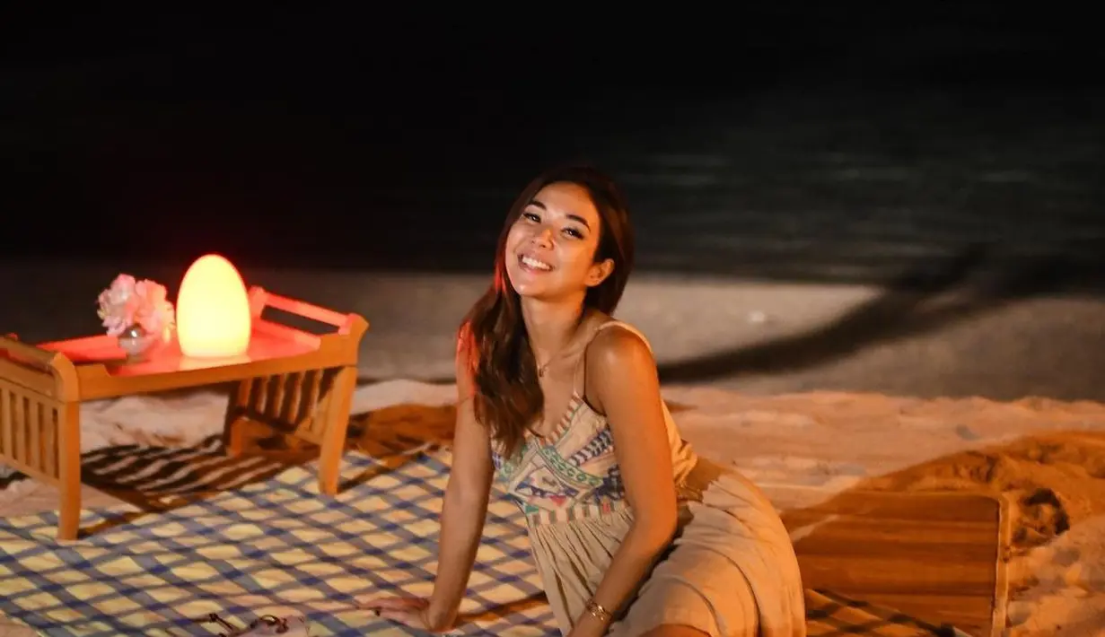 Saat makan malam di pinggir pantai, Gisella Anastasia tampil cantik dengan gaun strapline berwarna cokelat. Gaun sederhana ini memiliki motif warna warni di bagian dada. Warna gaunnya sendiri membuat Gisel menyatu dengan alam sekelilingnya.