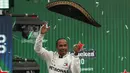 Pembalap Mercedes dari Inggris, Lewis Hamilton melempar topi sombrero merayakan keberhasilannya menjuarai balapan GP Meksiko di Autodromo Hermanos Rodriguez, Mexico City (28/10/2019). Kemenangan ini mendekatkan Hamilton ke titel juara dunia F1 2019. (AP Photo/Eduardo Verdugo)