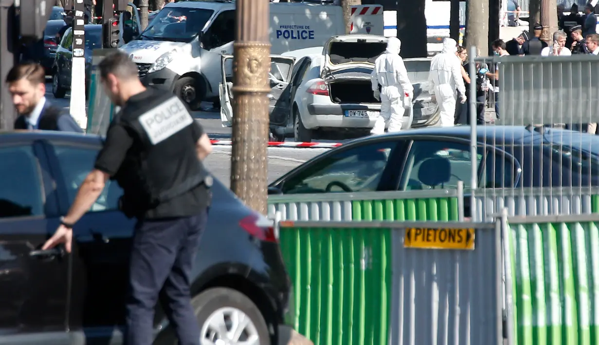 Tim penyelidik forensik memeriksa sebuah mobil usai insiden penyerangan di kawasan Champs Elysees, Paris, Senin (19/6). Kendaraan itu mengeluarkan api usai sengaja menabrak van milik polisi di lokasi wisata terkenal tersebut. (AP Photo/Thibault Camus)