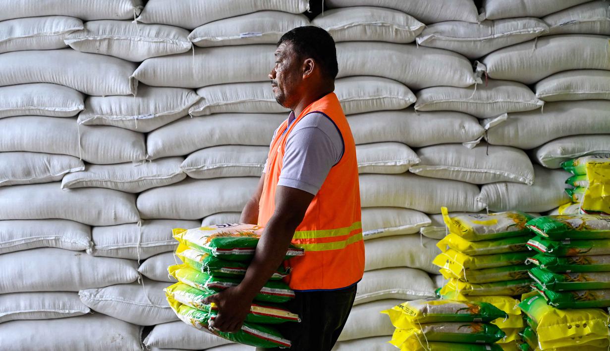 Sebelumnya, pemerintah memastikan bahwa stok Cadangan Beras Pemerintah (CBP) di Provinsi Aceh, Sumatera Utara (Sumut), dan Sumatera Barat (Sumbar) telah melebihi tiga kali lipat dari kebutuhan masyarakat. Tampak dalam foto, seorang pekerja membawa karung-karung beras di gudang Badan Urusan Logistik (Bulog) di Lambaro, Provinsi Aceh pada 29 Desember 2025. (CHAIDEER MAHYUDDIN/AFP)