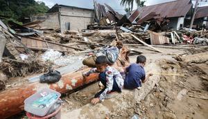 Hingga kini, tim gabungan dari BPBD, TNI, Polri, Basarnas, dan relawan terus melakukan pencarian terhadap warga yang masih hilang. Tampak dalam foto, anak-anak bermain di dekat rumah-rumah yang rusak di sebuah desa yang terdampak banjir bandang di Batang Toru, Sumatera Utara, Senin 1 Desember 2025. (AP Photo/Binsar Bakkara)