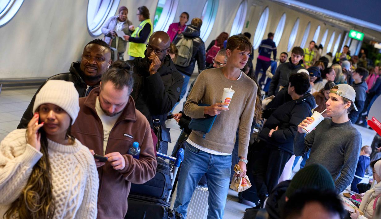 Sementara itu, otoritas di Belanda telah mengeluarkan imbauan agar warga untuk tetap berada di rumah, karena badai salju baru diperkirakan akan datang pada malam hari. Tampak dalam foto, para pelancong yang terlantar mengantre di meja informasi di bandara Schiphol di Amsterdam, Belanda, Rabu 7 Januari 2026. (AP Photo/Peter Dejong)