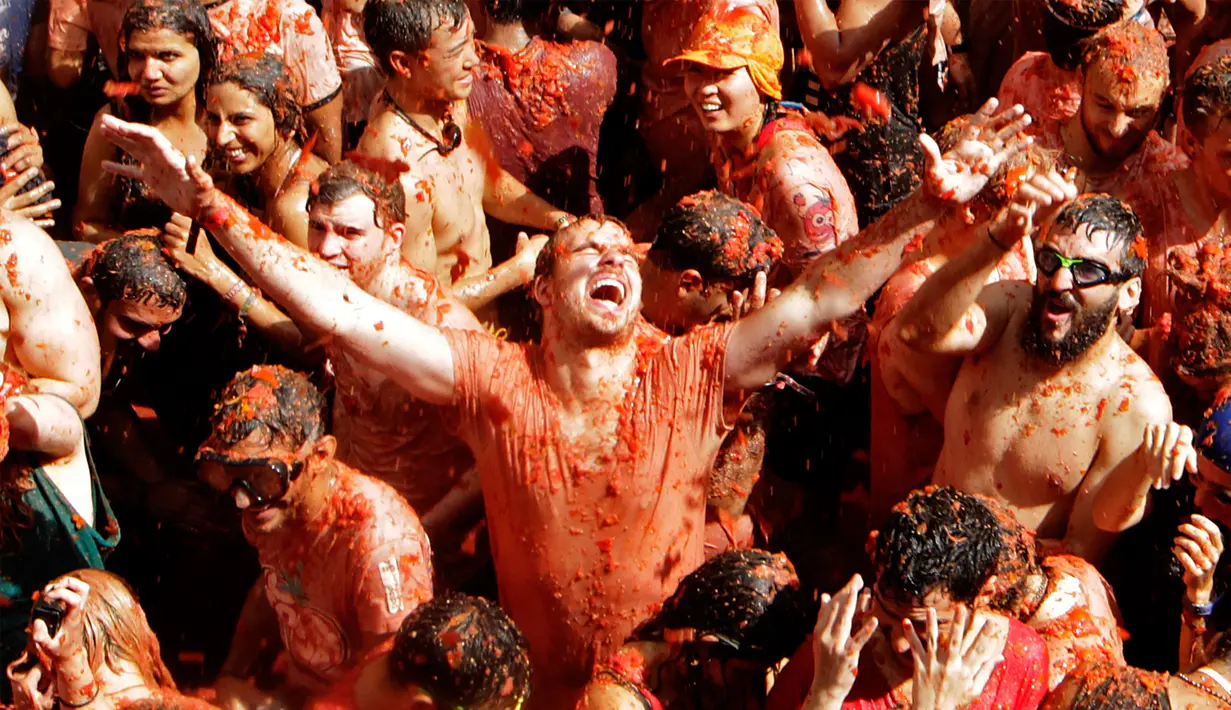 Para peserta menikmati butiran-butiran tomat dalam festival La Tomatina di desa Bunol, Spanyol, Rabu (30/8). Adu lempar tomat ini sudah dilakukan sejak 1945 oleh sekelompok anak-anak di daerah penghasil tomat Kota Valencia, Spanyol. (Alberto Saiz/AP)