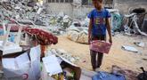 Seorang anak laki-laki menyelamatkan barang-barang dari reruntuhan rumahnya yang hancur akibat serangan Israel di Khan Younis, Jalur Gaza selatan, pada Rabu 29 Oktober 2025. Badan pertahanan sipil Gaza mengatakan pada Rabu 29 Oktober 2025 bahwa puluhan serangan Israel menghantam sejumlah wilayah. (BASHAR TALEB/AFP)