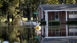 Parker Uzzell mendayung kano untuk melintasi banjir yang merendam wilayah Lumberton di Carolina Utara, Amerika Serikat, 12 Oktober 2016. Banjir akibat badai Matthew tersebut merendam kota berpenduduk 21.000 orang itu. (REUTERS/Randall Hill)