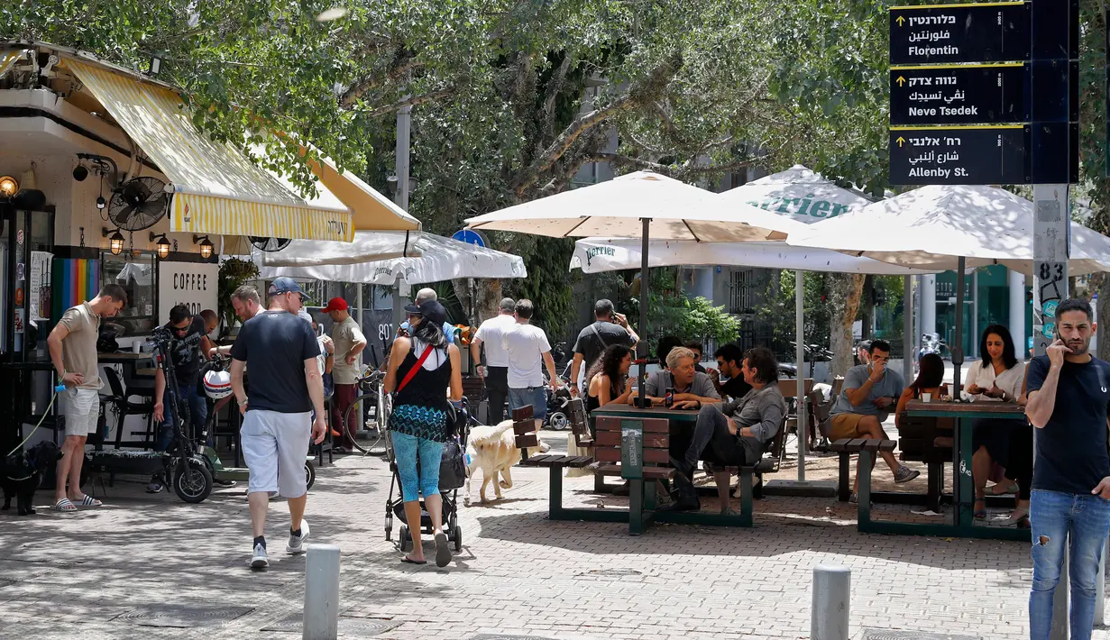 Orang-orang duduk di luar sebuah kafe di kota pantai Mediterania Israel di Tel Aviv, Rabu (27/5/2020). Setelah lebih dari dua bulan, Israel pertama kalinya mengizinkan restoran hingga kafe dibuka kembali usai pelonggaran pembatasan yang diberlakukan untuk mencegah Covid-19. (JACK GUEZ/AFP)