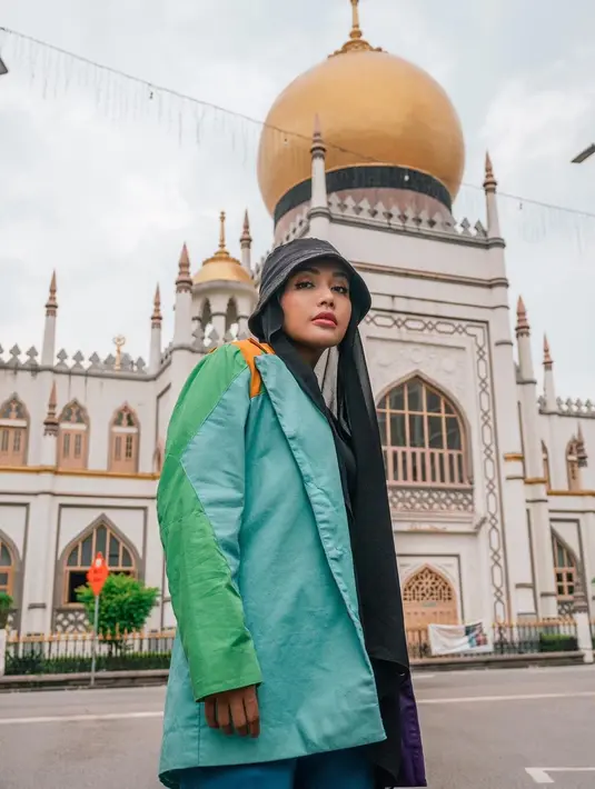 Denada tampil nyentrik dengan layering outfit warna-warni sambil berpose di masjid Sultan Arab, Singapura. [Foto: IG/denadaindonesia].