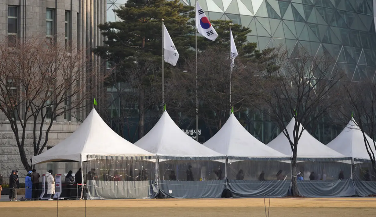 Orang-orang mengantre untuk tes virus corona COVID-19 sambil menjaga jarak sosial di klinik skrining sementara untuk virus corona dekat Balai Kota Seoul, Seoul, Korea Selatan, Rabu (26/1/2022). (AP Photo/Lee Jin-man)
