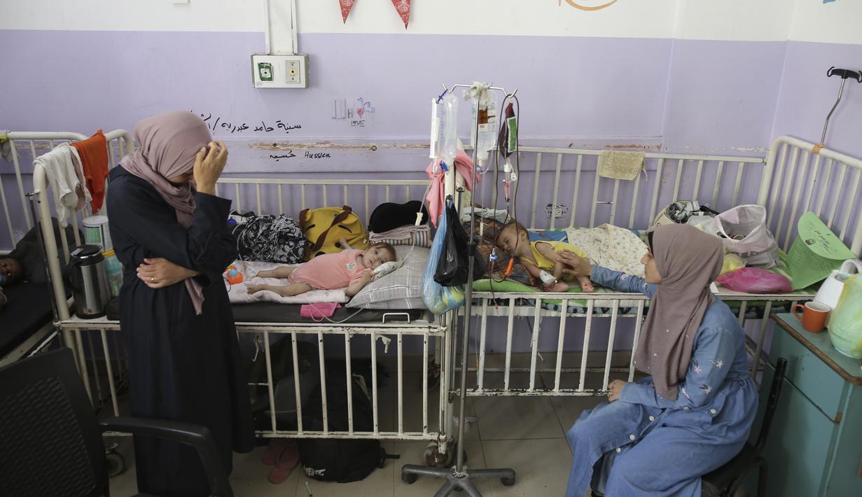 Amira Al-Jojo (kiri) berdiri di samping putranya yang berusia 10 bulan, Yousef Al-Jojo, yang menderita kekurangan gizi di Rumah Sakit Martir Al-Aqsa, tempat ia menjalani perawatan, di Deir al-Balah di Jalur Gaza tengah pada Sabtu, 1 Juni 2024. (AP Photo/ Jehad Alshrafi)