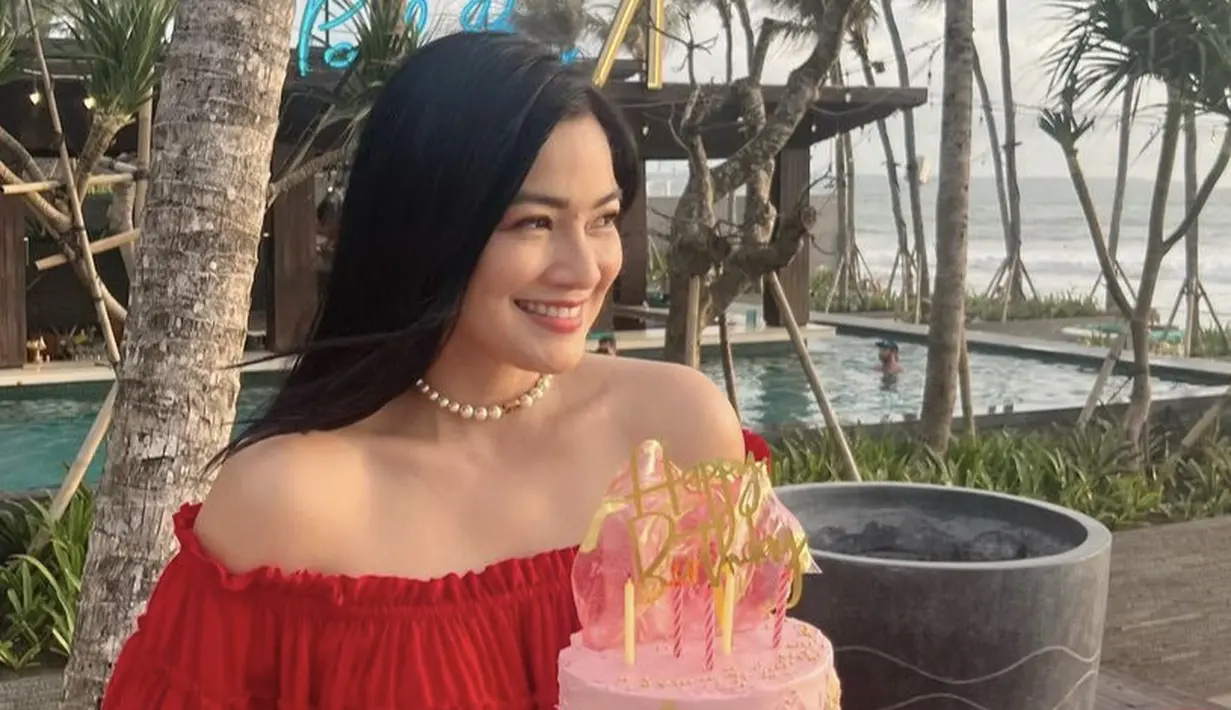 Sambil memegang cake ulang tahun pink, Titi Kamal mengenakan kalung cooker mutiara. Dengan riasan minimalis mengenakan eyeshadow cokelat dan lipstik pink.  (@titi_kamall)