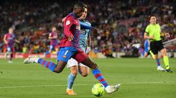 Pemain depan Barcelona Ousmane Dembele (kiri) berebut bola dengan gelandang Celta Vigo Fran Beltran pada laga lanjutan La Liga di Camp Nou, Rabu (11/5/2022) dini hari WIB. Barcelona menghajar Celta Vigo 3-1 di kandang sendiri. (LLUIS GENE / AFP)