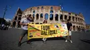 Para pengunjuk rasa memegang spanduk bertuliskan "kehabisan bahan bakar fosil" dalam bahasa Italia di depan Colosseum kuno Roma, Italia, Jumat (15/9/2023). Aksi iklim besar internasional pernah terjadi pada 2019 dalam gerakan Fridays for Future yang dimotori oleh aktivis iklim Swedia Greta Thunberg. (AP Photo/Alessandra Tarantino)