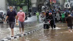 Pengendara mendorong sepeda motornya melewati banjir yang menggenangi kawasan Jalan Wolter Monginsidi Jakarta dan sekitarnya, Sabtu (20/2/2021). Hujan yang mengguyur Jakarta sejak Jumat (19/2) membuat sejumlah titik di Jakarta terendam banjir. (Liputan6.com/Helmi Fithriansyah)