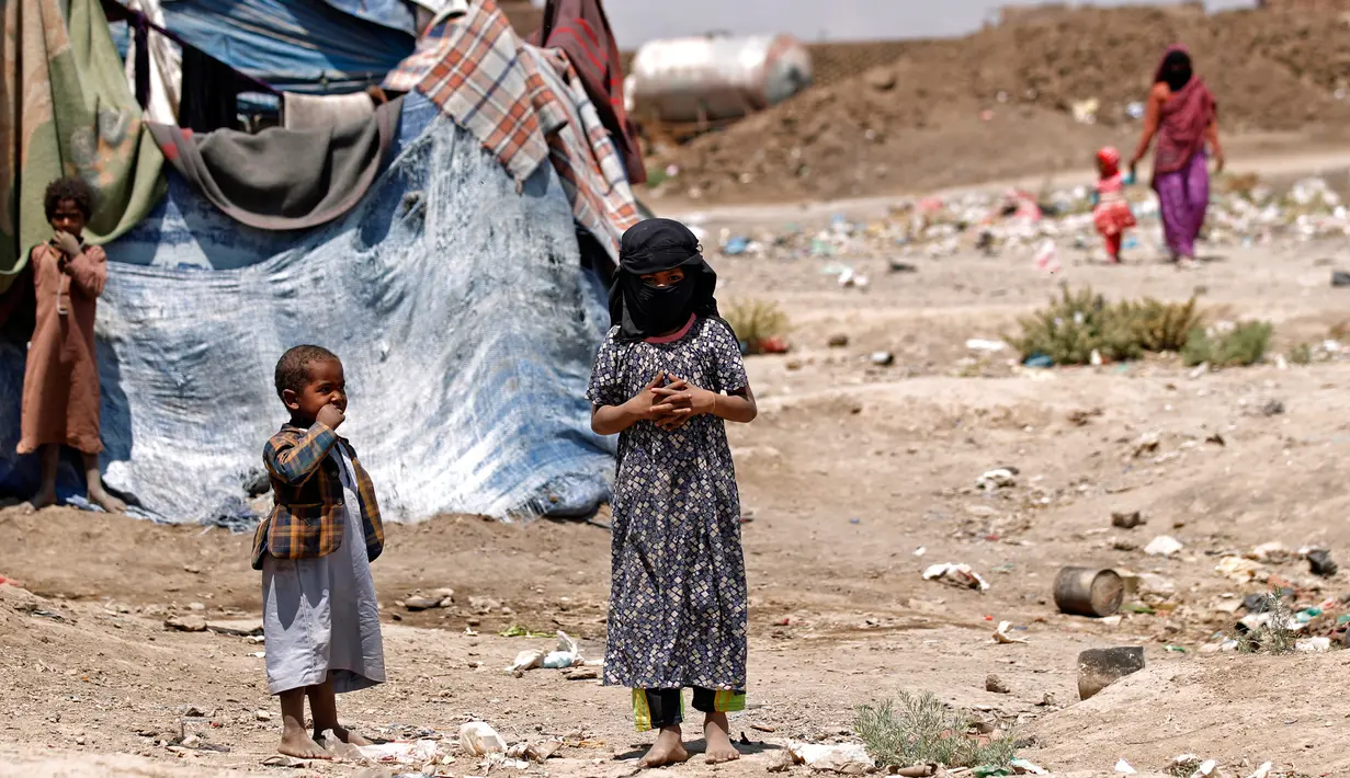 Sejumlah anak-anak Yaman berdiri dekat tenda pengungsian di kamp pengungsian di Sanaa, Yaman (15/4). WHO mencatat sebanyak 2,1 juta orang telah terlantar akibat konflik yang terjadi di Yaman. (AFP Photo / Mohammed Huwais)
