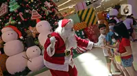 Petugas yang mengenakan kostum Sinterklas berinteraksi dengan anak-anak saat menghibur pengunjung di Senayan City Mall, Jakarta, Jumat (25/12/2020). Pengunjung bisa berswafoto dan menikmati momen Natal bersama keluarga dan orang terkasih dengan "Santa and Friend". (Liputan6.com/Herman Zakharia)