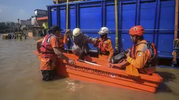 Banjir yang melanda sejumlah titik di Kabupaten Bandung juga menyebabkan 162 kepala keluarga (KK) atau sekitar 457 jiwa harus dievakuasi ke tempat pengungsian. Tampak dalam foto, tim penyelamat membantu seorang perempuan yang terjebak banjir di samping truk pengangkut kayu di Bandung, Jawa Barat, pada Jumat 5 Desember 2025. (TIMUR MATAHARI/AFP)