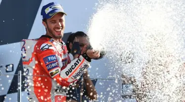 Pembalap Tim Ducati Corse, Andrea Dovizioso menyemprot sampanye saat merayakan kemenangannya di atas podium GP Inggris di Sirkuit Silverstone, Minggu (27/8). Dovizioso mengungguli dua pembalap Yamaha, Maverick Vinales dan Valentino Rossi. (OLI SCARFF/AFP)