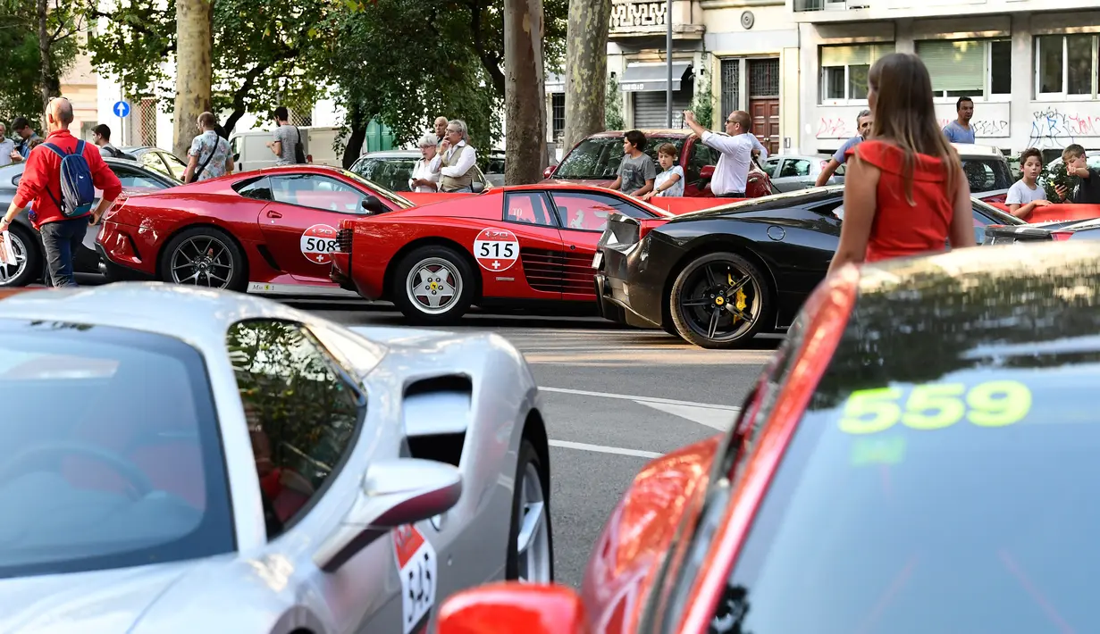 Sejumlah pengunjung melihat mobil Ferrari yang dipamerkan saat perayaan ulang tahun Ferrari ke-70 di Corso Sempione di Milan, Italia (8/9). (AFP Photo/Miguel Medina)
