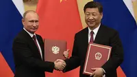Presiden Rusia Vladimir Putin (kiri) bersalaman dengan Presiden China Xi Jinping saat upacara penandatanganan kerja sama di Beijing, China (8/6). Untuk kali ke-25 Presiden Rusia Vladimir Putin bertemu dengan Presiden Xi Jinping. (AFP/Pool/Nicolas Asfouri)