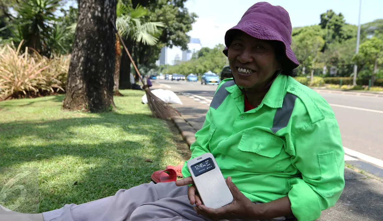 Sambil tersenyum, Ibu Tuti menunjukan ponsel baru miliknya hasil pemberian Gubernur DKI Jakarta, (24/3). Wanita 54 tahun ini mendapatkan hadiah ponsel karena aksinya yang berani memarahi pendemo perusak Balai Kota. (Liputan6.com/Yoppy Renato)