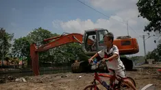 Seorang bocah bersepeda asyik memperhatikan pengerukan Kali Sidang, Jakarta, Jumat (19/9/2014) (Liputan6.com/Faizal Fanani)