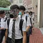 Para siswa sekolah mengenakan topeng dan helm berjalan di luar St. Paul's College selama protes di Hong Kong, Selasa (3/9/2019). Puluhan ribu siswa di Hong Kong mogok sekolah di hari pertama tahun ajaran baru. (AP Photo/Kin Cheung)