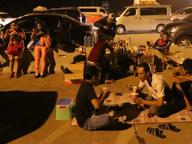 Sejumlah pemudik tengah beristirahat sambil menikmati makanan yang dijajakan pedagang di pinggir Tol Cikopo, Jawa Barat, Jumat (1/7). Kemacetan di sepanjang jalur tersebut dimanfaatkan pedagang untuk berjualan di sekitar lokasi (Liputan6.com/Angga Yuniar)