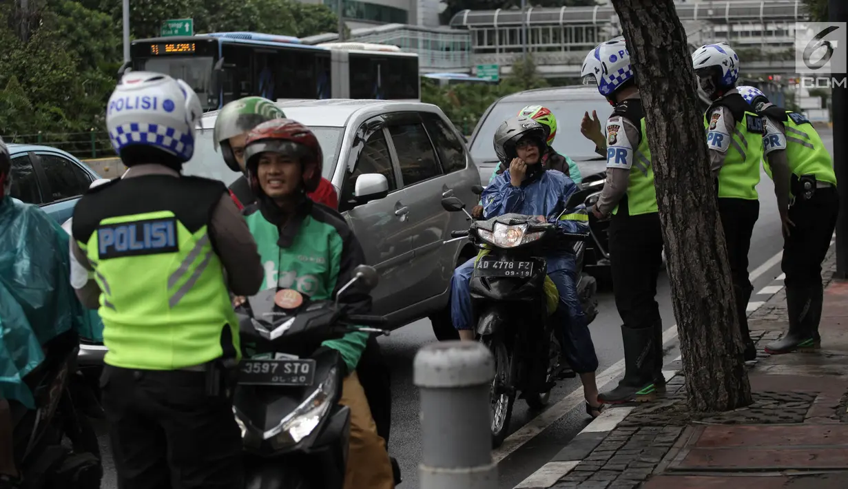 Polisi melakukan tindakan tilang kepada pengendara motor yang melanggar aturan jalur khusus sepeda motor di Jalan MH Thamrin-Medan Merdeka Barat, Jakarta Pusat, Kamis (8/2). (Liputan6.com/Arya Manggala)