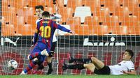 Striker Barcelona, Lionel Messi, mencetak gol ke gawang Valencia pada laga Liga Spanyol di Stadion Mestalla, Minggu (2/5/2021). Barcelona menang dengan skor 2-3. (AFP/Jose Jordan)