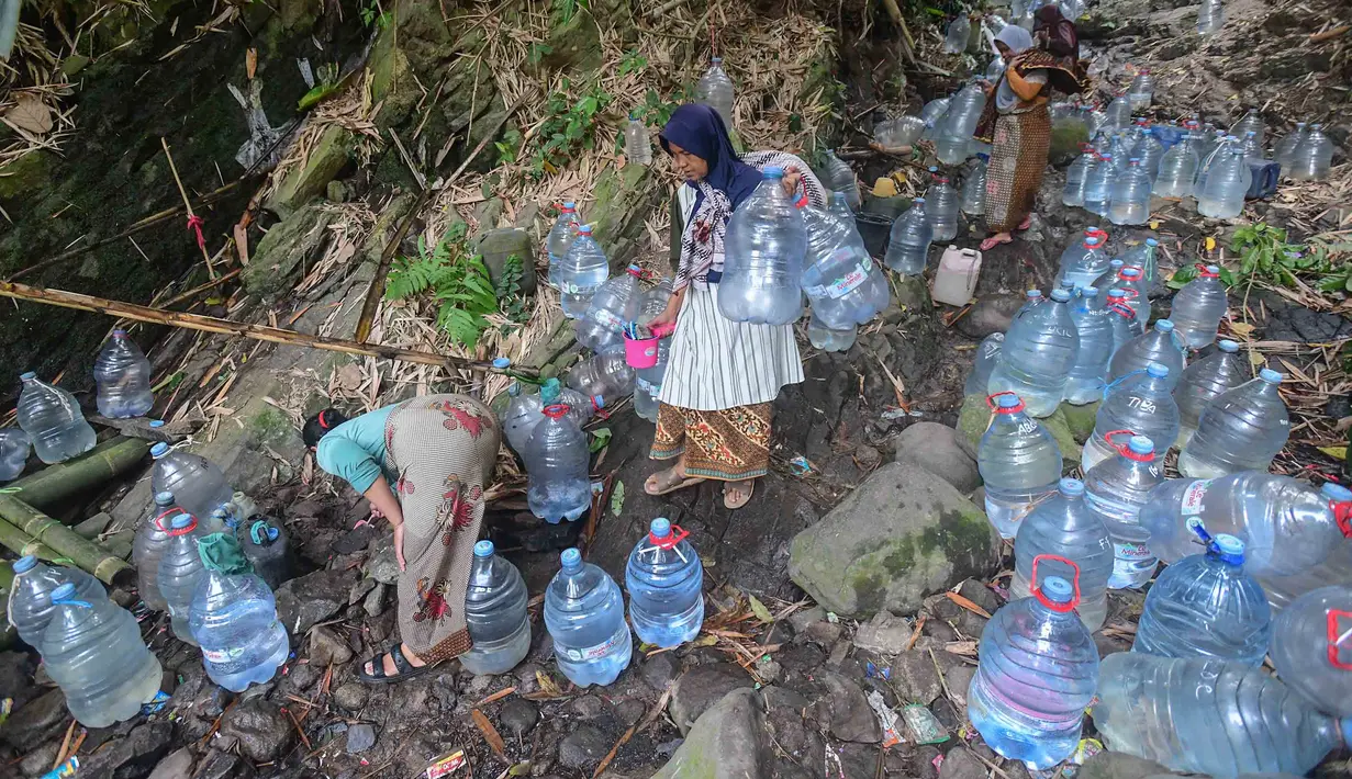 Warga berjalan untuk mengambil air untuk minum dan kebutuhan mck rumah  di sumber mata air Sumur Bendung, Gunung Batur, Kota Cilegon, Banten, Minggu, (15/7/2026). (KLY/Arie Basuki)