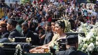 Pasangan pengantin Kaesang Pangarep dan Erina Gudono menaiki kereta saat prosesi kirab Ngunduh Mantu di kawasan Selamet Riyadi, Solo, Jawa Tengah, Minggu (11/12/2022). Kirab ngunduh mantu pernikahan putra bungsu Presiden Joko Widodo, Kaesang Pangarep dan istrinya Erina Gudono yang dimulai dari Loji Gandrung menuju Pura Mangkunegaran tersebut disaksikan ribuan masyarakat Solo dan sekitarnya. (Liputan6.com/Herman Zakharia)