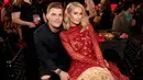 Paris Hilton dan tunangannya Chris Zylka duduk bersama saat menghadiri iHeartRadio Music Awards 2018 di Inglewood, California (11/3). Paris Hilton tampil cantik mengenakan busana merah dan Chris Zylka tampil dengan jas hitam. (AFP Photo/Christopher Polk)