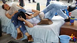 Dua wanita berbaring di tempat tidur saat merayakan Hari Malas Sedunia di Ibague, Kolombia, (14/8). Sejumlah orang turun ke jalan membawa tempat tidur dan maainanya untuk bermalas-malasan. (REUTERS/Fredy Builes)