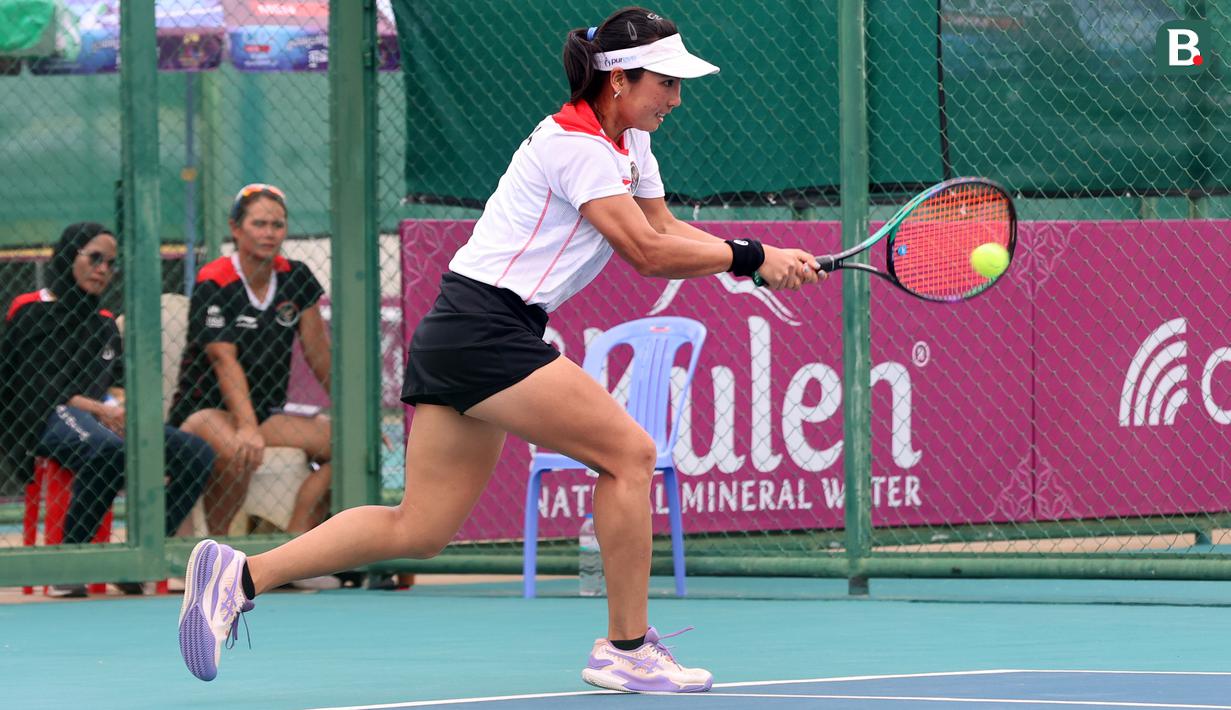 Petenis putri Indonesia, Aldila Sutjiadi berusaha mengembalikan bola ke arah petenis Thailand, Aunchisa Chanta pada pertandingan final tenis beregu putri SEA Games 2023 di Tennis Arena, Morodoc Techo National Stadium, Phnom Penh, Kamboja, Selasa (9/5/2023). Indonesia sempat tertinggal di partai pertama namun sukses menyamakan kedudukan saat partai kedua. Pasangan Aldila dan Jessy kemudian sukses menyegel kemenangan partai ketiga sekaligus memberikan emas ke-24 untuk Indonesia. (Bola.com/Abdul Aziz)