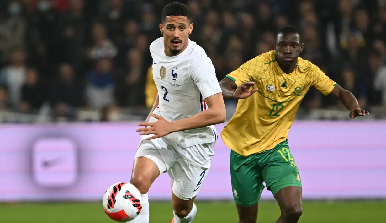 Bek Prancis William Saliba berebut bola dengan penyerang Afrika Selatan Bongokuhle Hlongwane dalam laga persahabatan di Stadion Pierre Mauroy, Rabu (30/3/2022) dinihari WIB. Timnas Prancis berpesta lima gol ke gawang Afrika Selatan. (DENIS CHARLET / AFP)