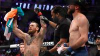 Wasit (tengah) mengangkat tangan Conor McGregor setelah mengalahkan Donald 'Cowboy' Cerrone pada pertarungan kelas welter UFC 246 di T-Mobile Arena, Las Vegas, Amerika Sertikat, Sabtu (18/1/2020). McGregor mengalahkan Cowboy pada detik ke-40. (Steve Marcus/Getty Images/AFP)