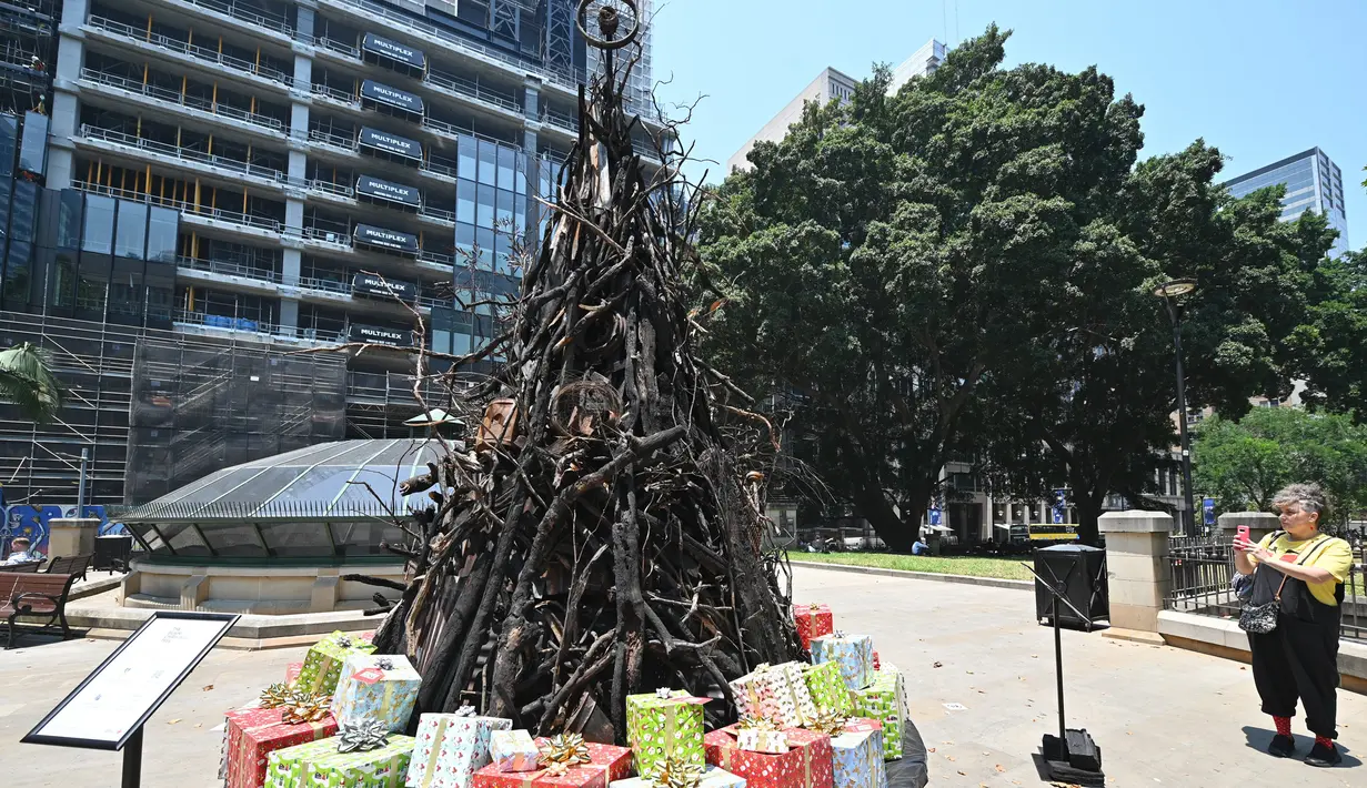 Seorang wanita megambil foto instalasi yang dijuluki 'Pohon Natal yang Terbakar' di Sydney (18/12/2019). Instalasi Pohon Natal ini untuk mendukung Dana Bantuan dan Pemulihan Bencana Palang Merah Australia di tengah situasi kebakaran hutan. (AFP/Peter Parks)