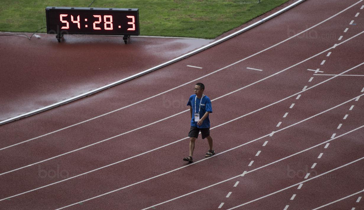 Seorang pekerja melewati lintasan lari di Stadion Utama Gelora Bung Karno, Jakarta, Jumat (9/8/2018). Lokasi ini akan dijadikan venue dari invitation tournament cabang atletik. (Bola.com/Vitalis Yogi Trisna)