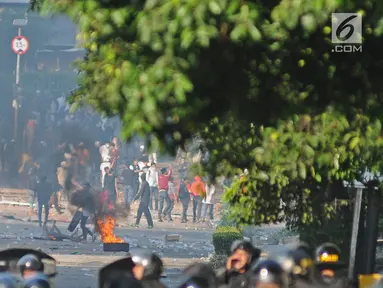 Bentrok antara polisi dan massa aksi di kawasan Tanah Abang, Jakarta, Rabu (22/5/2019).  Beberapa kelompok massa menggunakan benda-benda keras hingga mercon untuk menahan laju petugas keamanan. (Liputan6.com/Herman Zakharia)