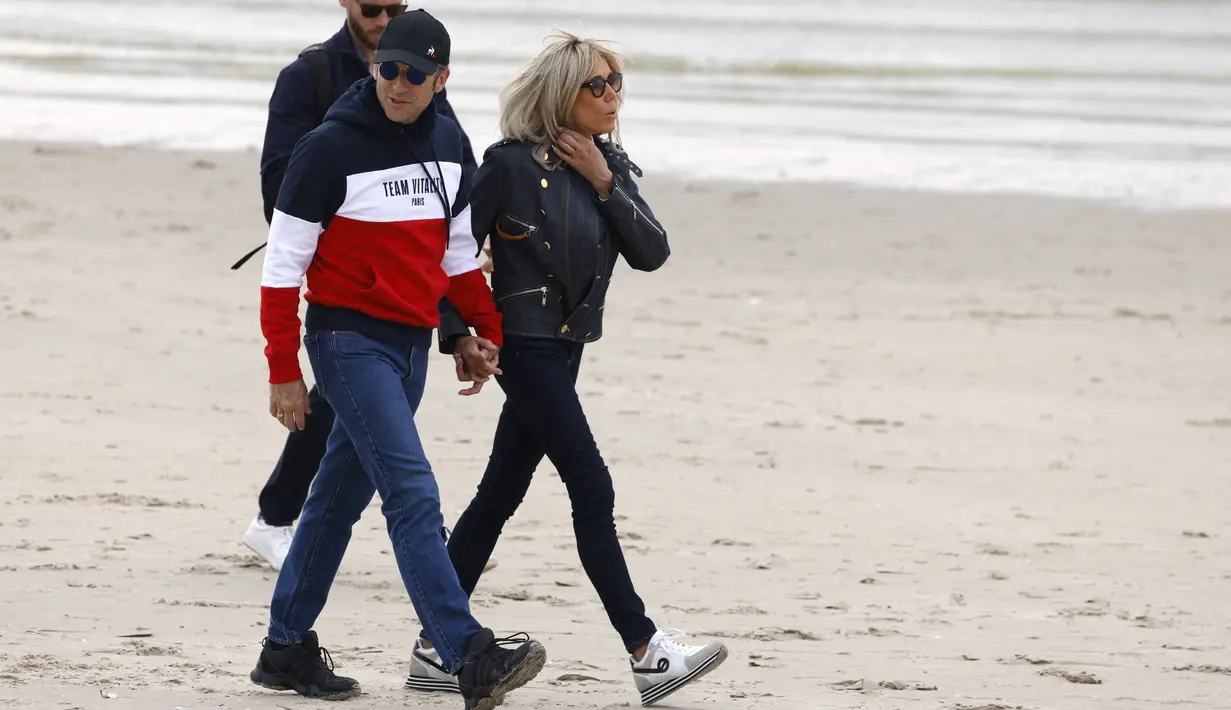 <p>Presiden Prancis Emmanuel Macron dan istrinya Brigitte Macron berjalan di sepanjang pantai di Le Touquet, menjelang putaran kedua pemilihan presiden Prancis, Sabtu (23/4/2022). Emmanuel Macron akan menghadapi Marine Le Pen dalam putaran kedua pemilihan presiden (pilpres) pada 24 April 2022. (Ludovic MARIN / AFP)</p>
