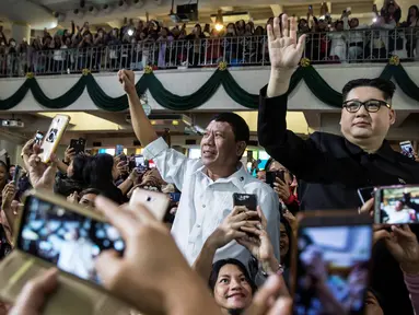 Peniru Presiden Filipina Rodrigo Duterte, Cresencio Extreme (tengah) dan peniru pemimpin Korea Utara Kim Jong Un, Howard X melambaikan tangan ketika menghadiri kebaktian gereja di pusat Hong Kong pada 3 Februari 2019. (ISAAC LAWRENCE/AFP)