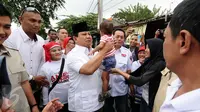 Ketua Umum Partai Gerindra, Prabowo Subianto (tengah) menggendong seorang anak saat tiba di wilayah kelurahan Pinang Ranti, Jakarta, Selasa (31/1). Kedatangan Prabowo untuk mengkampanyekan Cagub DKI Jakarta Anies-Sandi. (Liputan6.com/Helmi Fithriansyah)