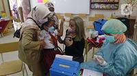 Tenaga kesehatan menyuntikkan vaksin COVID-19 kepada siswa di SDN 01 Depok, Depok, Jawa Barat, Selasa (14/12/2021). Vaksinasi untuk anak usia 6-11 tahun dilakukan di beberapa sekolah di Jakarta, Depok, dan Tangerang Selatan. (Liputan6.com/Herman Zakharia)